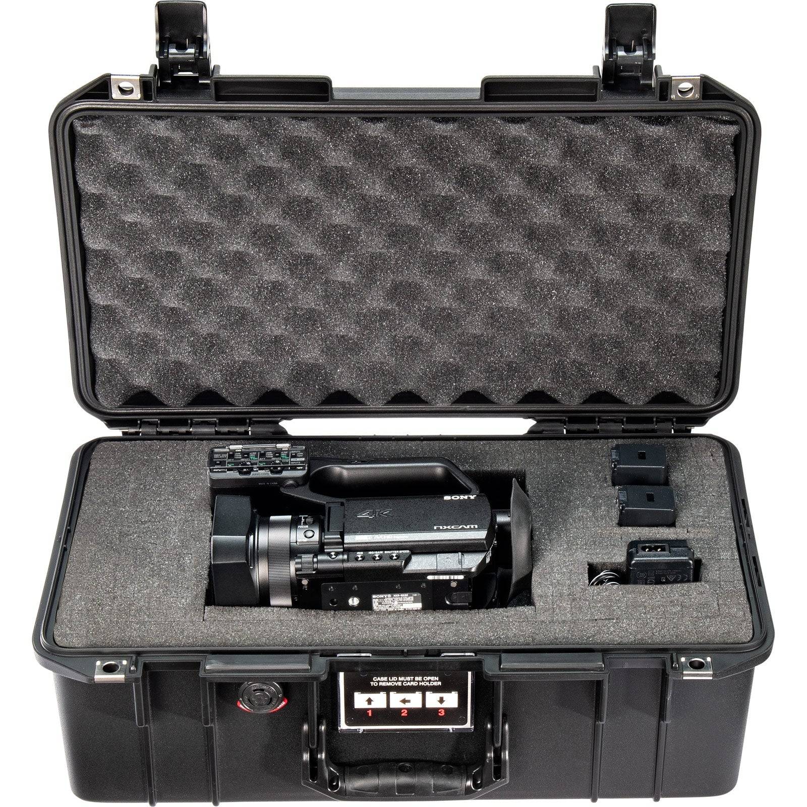 The 1506 Air Case, a lightweight waterproof PELI protective case with custom foam, securely holds a professional video camera, two batteries, and accessories—all neatly organized inside.
