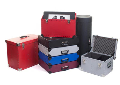 A group of colorful hard cases and boxes, some open to reveal foam interiors, stacked and arranged on a white background.