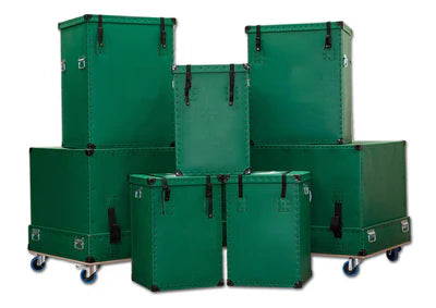 Six green, rectangular storage trunks of various sizes are stacked together; two have wheels and four have buckled straps and metal hardware.