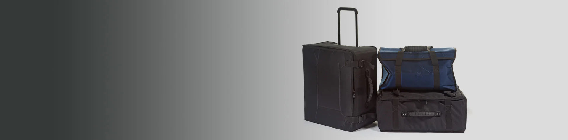 Two black duffle bags, one with wheels and an extended handle, are placed upright and side by side against a plain background.