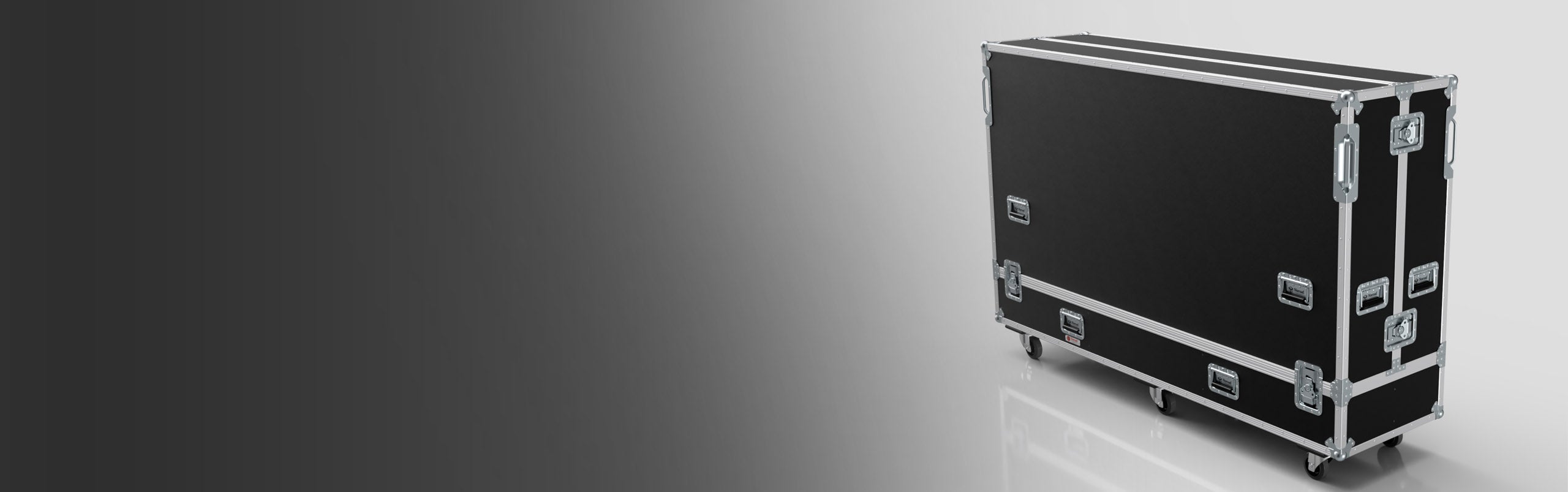 A large black equipment case with metal edges and handles sits on wheels against a grey background.