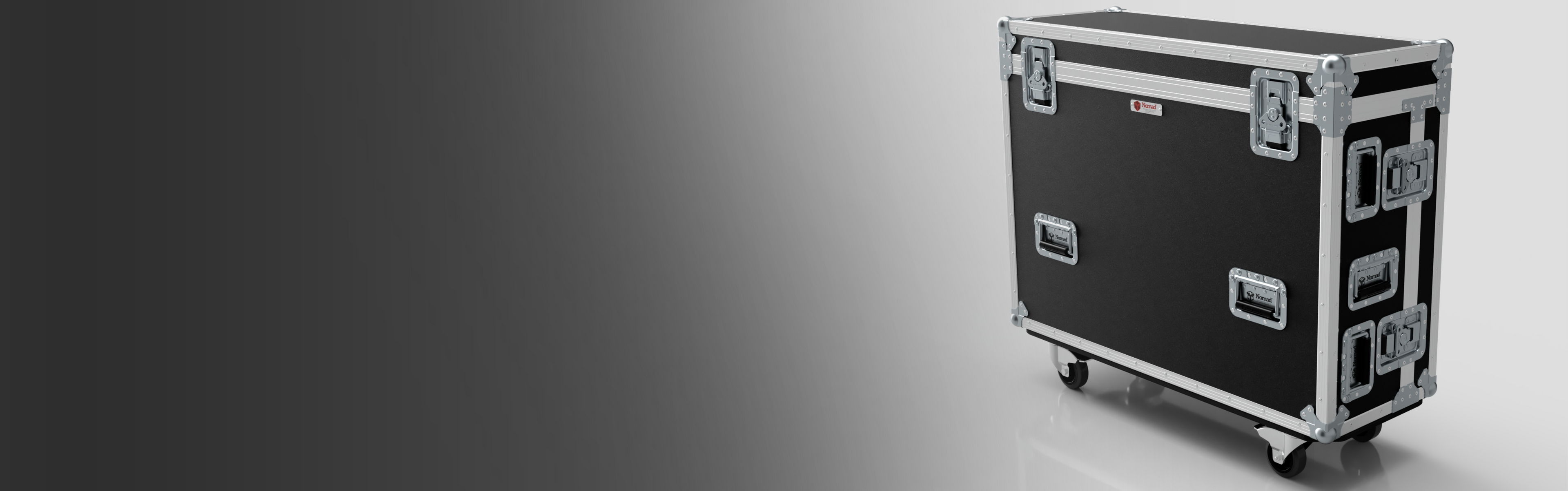 A large black and silver equipment case with metal reinforcements and four caster wheels, positioned on a smooth grey surface.