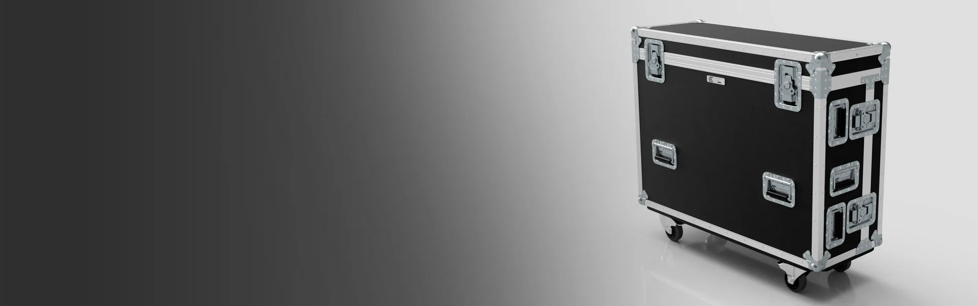 A large black equipment case with metal edges and handles sits on four caster wheels against a gray gradient background.