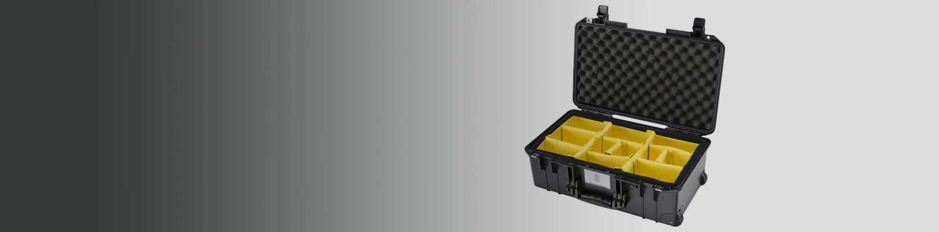 A black hard-shell case with yellow compartment dividers and foam padding in the lid, open against a gradient grey background.
