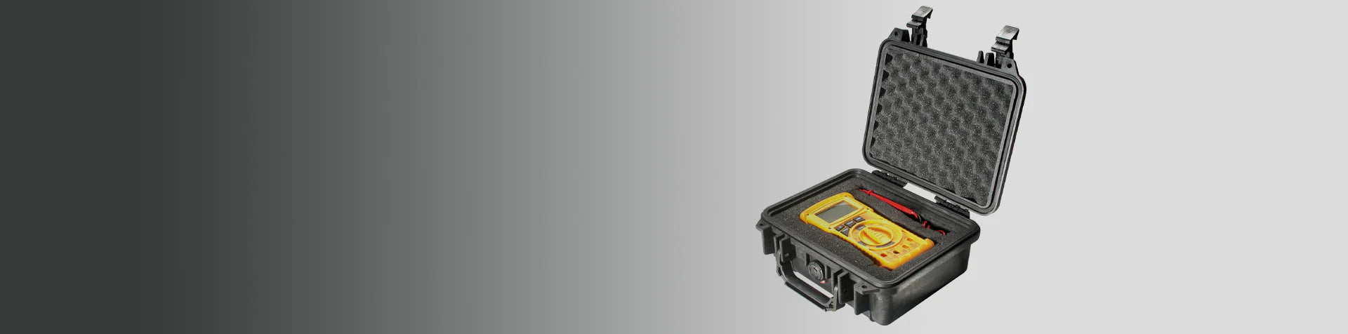 A yellow digital multimeter and red-black test leads in a black foam-padded hard case with an open lid, placed on a grey gradient background.