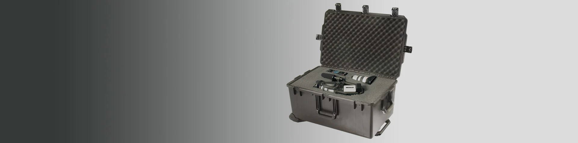 A hard-shell protective case with foam inserts, holding camera equipment and accessories, sits open on a grey and white background.