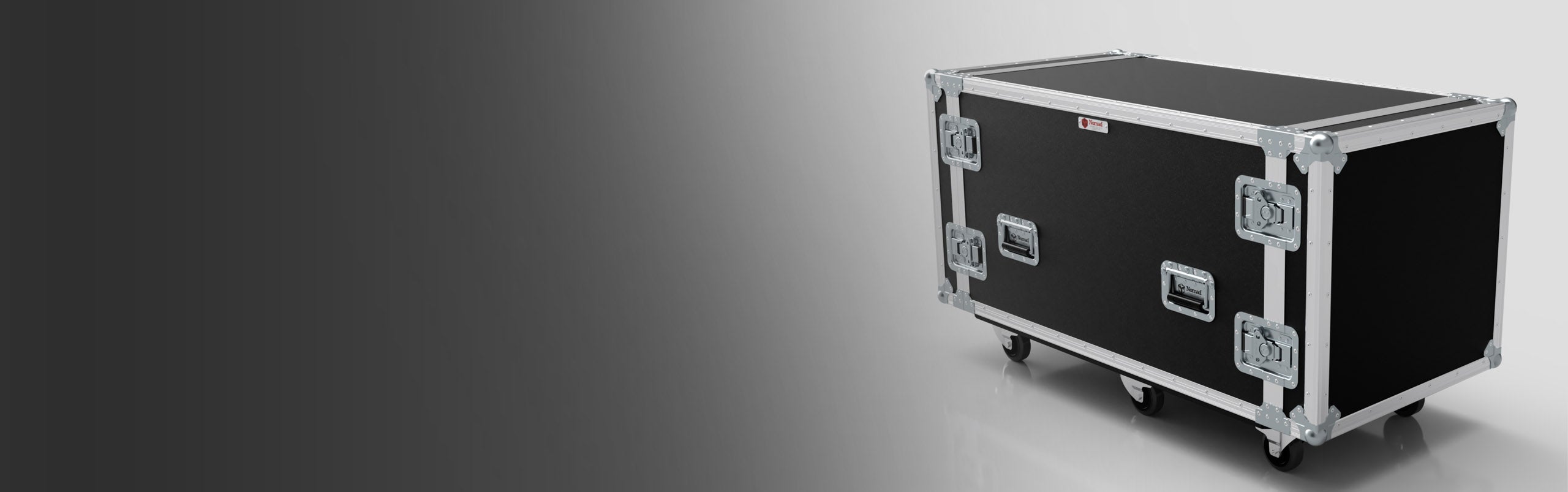 A large black road case with metal edges and latches, standing on four caster wheels, sits on a gray surface with a gradient background.