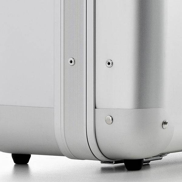 Close-up of the ALUpur 98800 case’s corner, highlighting its silver anodised aluminium shell, metal rivets, rounded edges, and two small black wheels on a light surface.