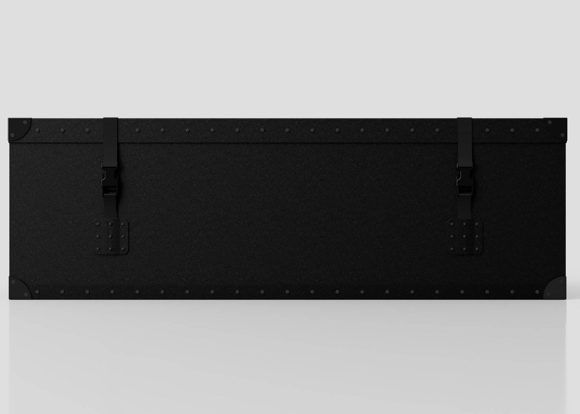 The Standard Long Storage Box - Medium is a large black rectangular case with metal corners, two webbing straps with side-release buckles, and rivet details, shown against a plain light gray background.