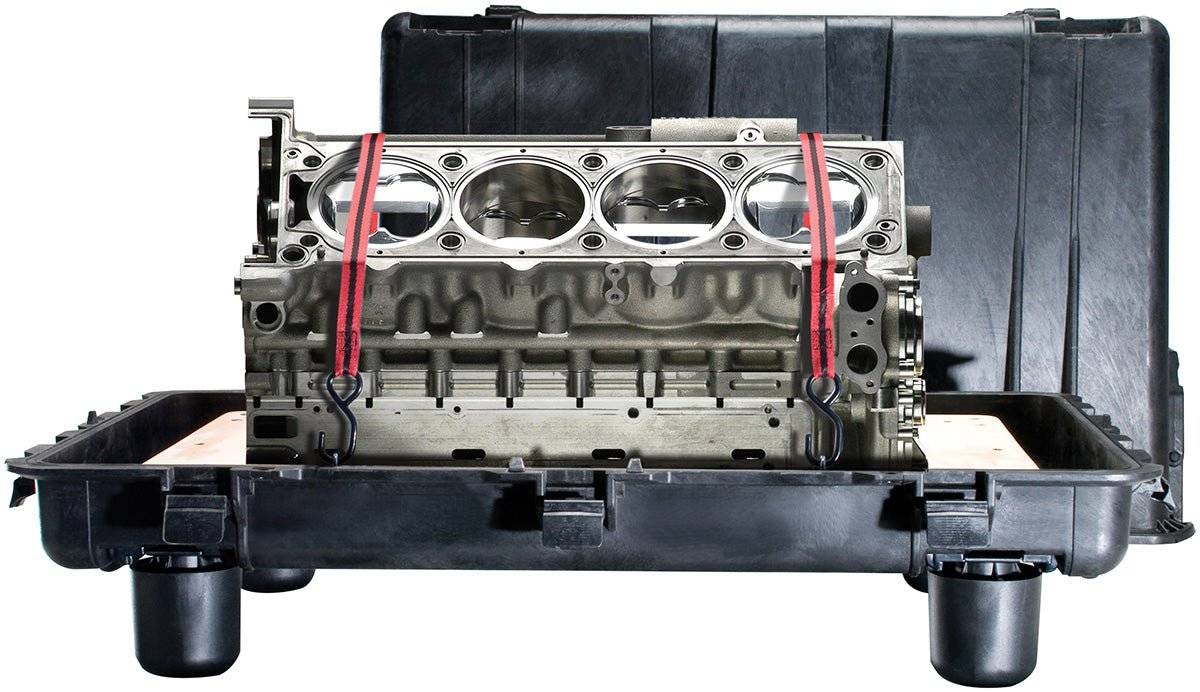 A metal engine block secured with red straps inside a PELI 0500 Protector Transport Case—a crushproof, watertight case built for ultimate protection.