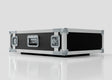 The 2U Suspended Shock Mounted Rack Case, a large rectangular black and silver case with metal-reinforced corners and latches, sits on a reflective white surface and provides superior protection with its shock mounted rack.