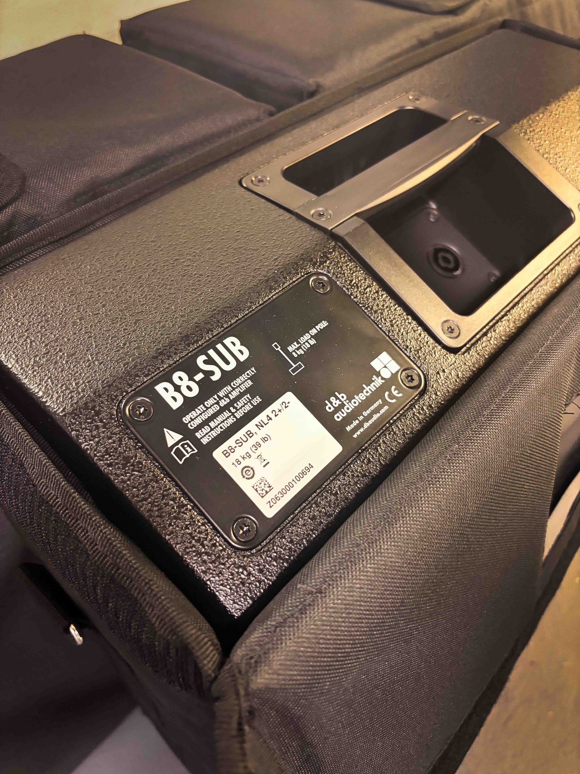 Close-up of the DB Audio D8 Sub Woofer Custom Cover protecting a black B8-SUB subwoofer, with technical specifications and manufacturer details visible on the metal plate, highlighting its road-ready durability.