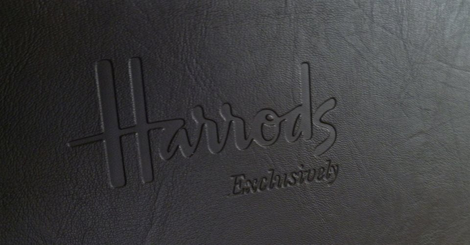 Close-up of a black textured surface with the words Harrods Exclusively embossed on it.