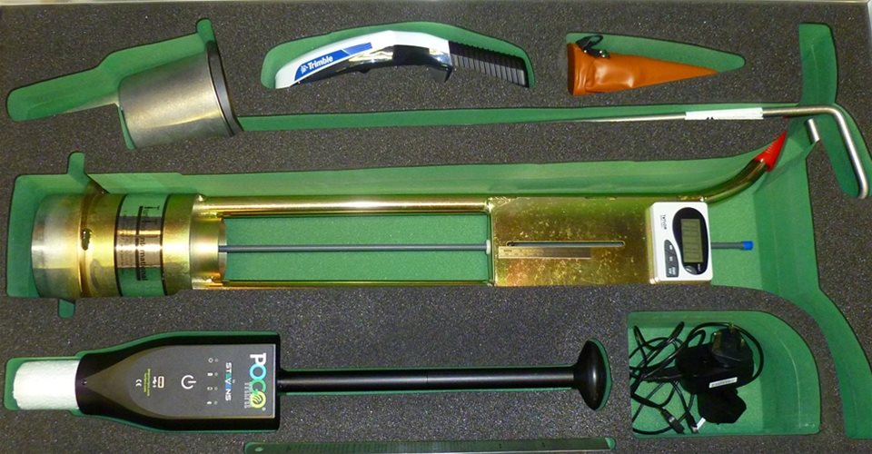 A set of specialized golf course maintenance tools, including a soil profiler, moisture meter, measuring cup, and other equipment arranged in a foam case.