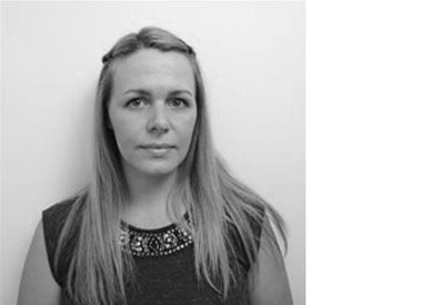 Black and white photo of a woman with long, straight hair, wearing a sleeveless top with a decorative neckline, against a plain background.