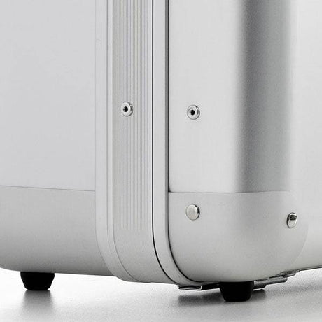 Close-up of the ALUpur 98800 case’s corner, highlighting its silver anodised aluminium shell, metal rivets, rounded edges, and two small black wheels on a light surface.