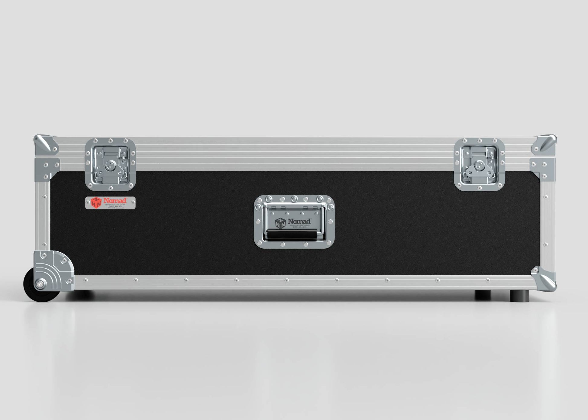 The Lid Maker Trunk Case is a rectangular black and silver flight case with metal edges, handles, latches, a red Nomad label on a plain gray background; its external dimensions are 1010 x 400 x 410 mm.