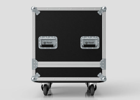 The Medium Motorsport Engine Flight Case (775 x 650 x 650 mm) is a black, rectangular case with metal reinforcements, two Nomad-branded handles, and four caster wheels, shown against a plain background.
