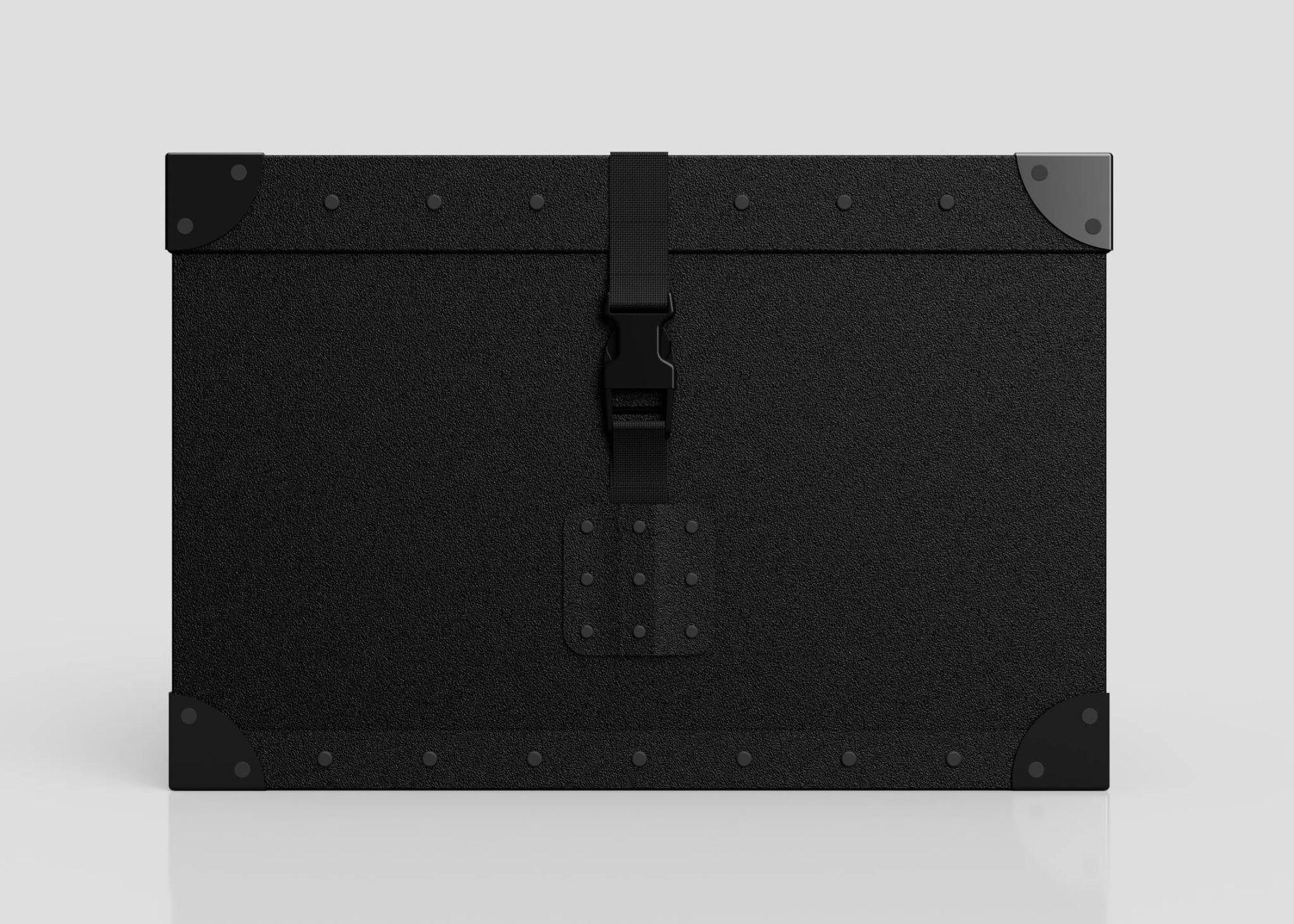 The Standard Cube Storage Box - Small is a black, rectangular trunk featuring metal corner protectors, a central latch, visible edge rivets, and a strong webbing buckle, shown against a plain light background.