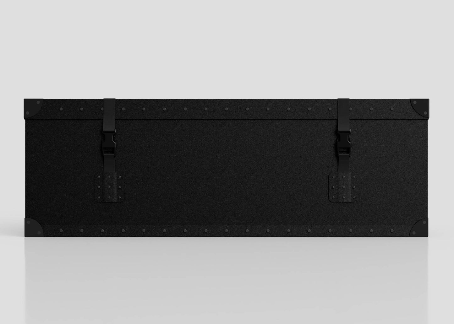 The Standard Long Storage Box - Small is a large black rectangular trunk with metal corners, rivet details, two front webbing buckle straps, and a sturdy zinc drop handle, shown against a plain light background.