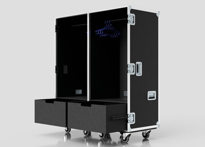 The Touring Wardrobe Case with Shoe Drawers is a black, wheeled storage trunk featuring two open sections, hanging hooks with blue hangers, two bottom drawers, and external dimensions of 1179 x 680 x 1569 mm.